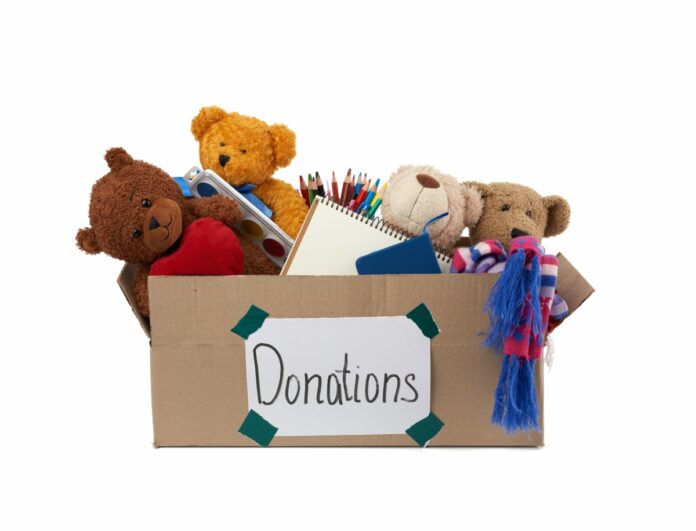 É tempo de doar brinquedos junto com as crianças; imagem mostra caixa de papelão com ursos de pelúcia dentro e materiais de escola