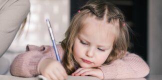 Seu filho sabe segurar o lápis corretamente? Veja como ajudá-lo; imagem mostra menina de 4 ou 5 anos escrevendo em um caderno