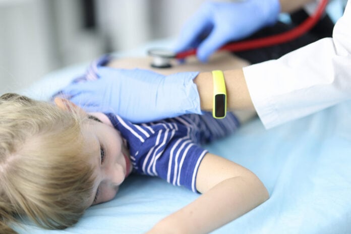 Pneumonia segue como principal causa de morte de crianças no país; imagem mostra criança deitada e médico ouvindo seu pulmão com estetoscópio
