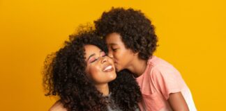 7 dicas para promover uma educação livre do machismo; imagem mostra criança morena dando beijo na mãe morena