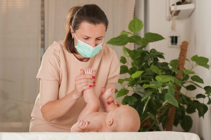 Ministério da Saúde alerta sobre uso de máscara em recém-nascidos e criança de até 2 anos; imagem mostra mãe usando máscara e segurando perna de bebê deitado