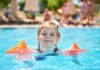 SBP alerta para risco de afogamento das crianças ao ficarem sozinhas em piscinas, sem supervisão de um adulto; imagem mostra menina em piscina com boias nos braços