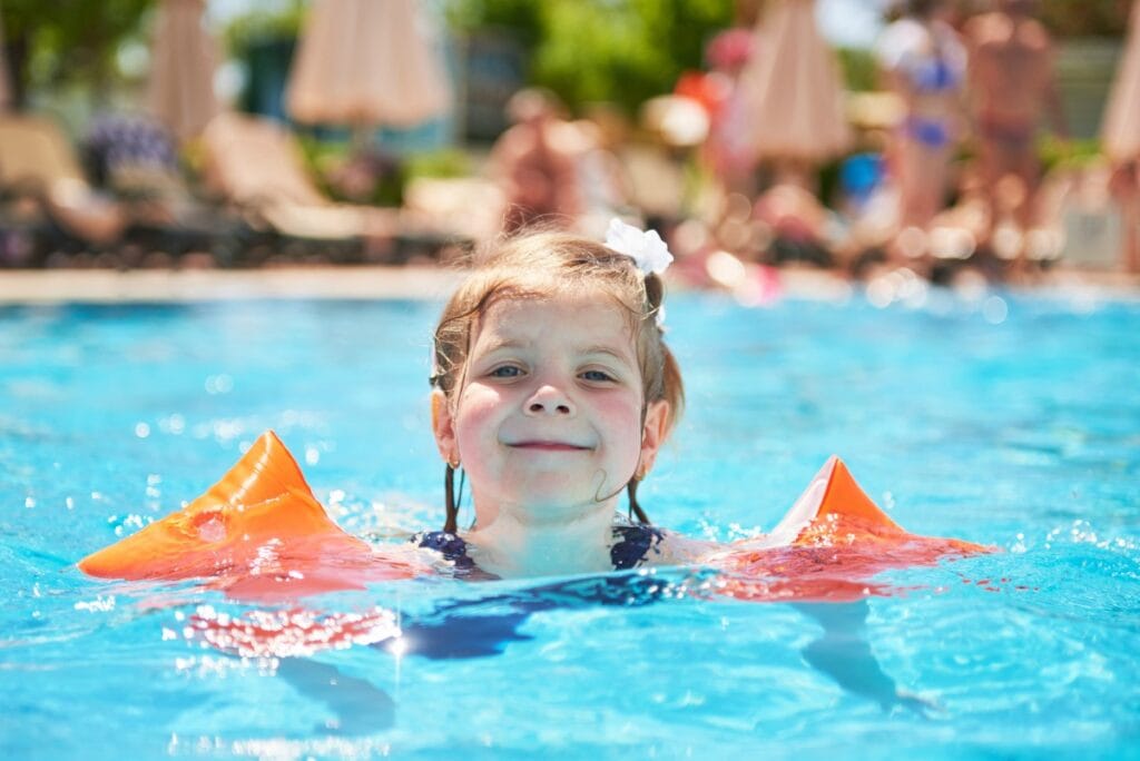 SBP alerta para risco de afogamento das crianças ao ficarem sozinhas em piscinas, sem supervisão de um adulto; imagem mostra menina em piscina com boias nos braços