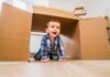 12 brincadeiras para divertir e ensinar crianças de todas as idades!; menino sorridente anda dentro de caixa de papelão