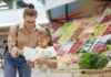 4 dicas para agir de forma pro ativa e evitar o mau comportamento infantil; mãe confere lista de compras com filha junto a seção de verduras do supermercado