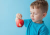 8 formas de ajudar as crianças a experimentar novos alimentos; menino segurando maçã