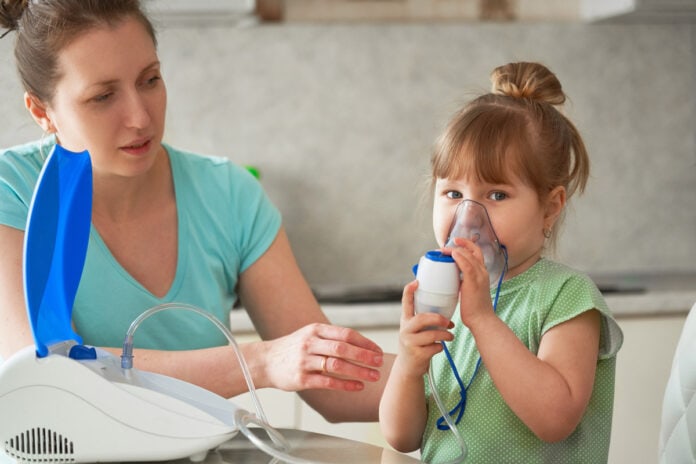 Doenças infecciosas em crianças diminuíram em meio à pandemia; criança usa nebulizador acompanhada da mãe