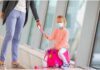 Brasil exige teste de covid-19 de para entrar no Brasil, exceto de crianças; garota sentada em cima da mala com mão dada com a mãe em aeroporto