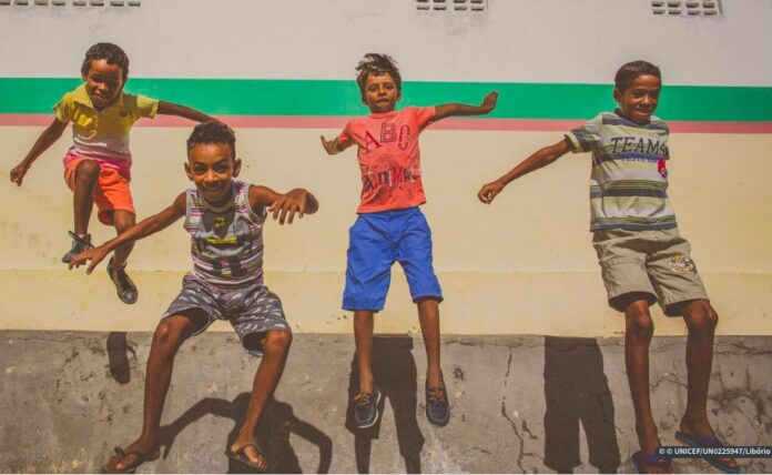nicef: pobreza infantil vai se manter elevada durante cinco anos; quatro meninos saltam e aparecem suspensos no ar
