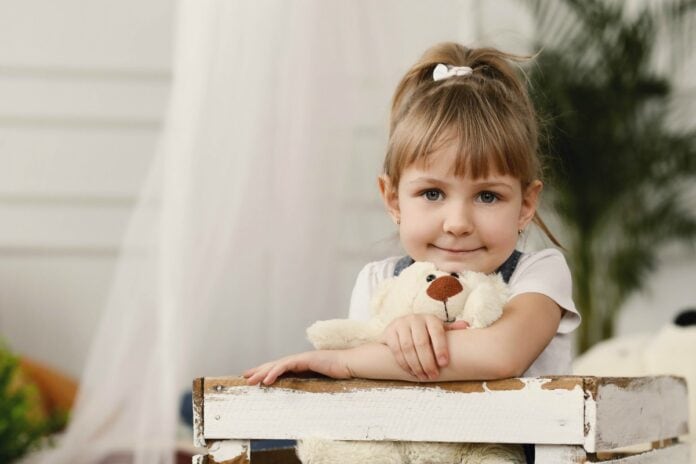 Crianças precisam saber que são antifrágeis e evoluem com os desafios; garota está abraçada a urso de pelúcia branco e olha fixamente para a câmera