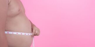 Menino obeso medindo barriga com fita métrica