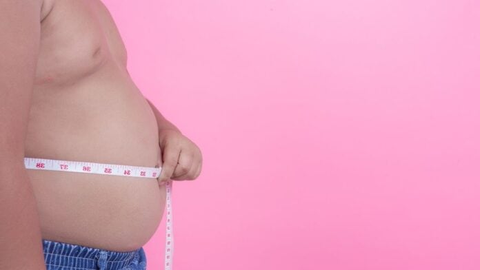 Menino obeso medindo barriga com fita métrica