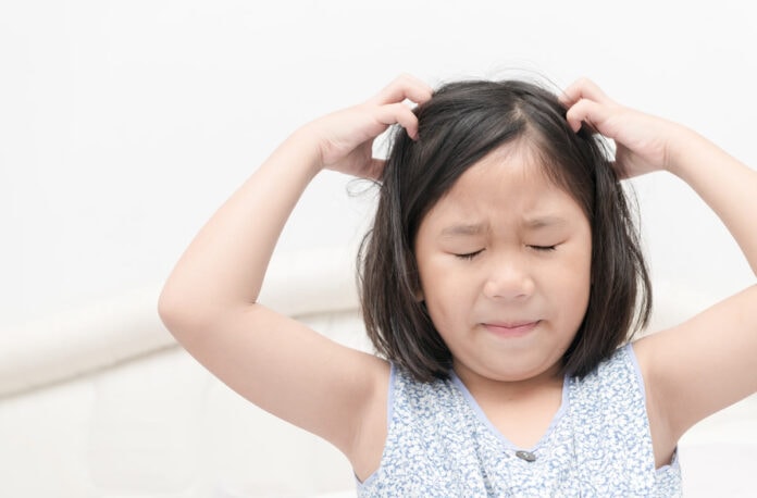 Piolhos em crianças: conheça os riscos e tratamentos; Menina coçando o cabelo com as mãos