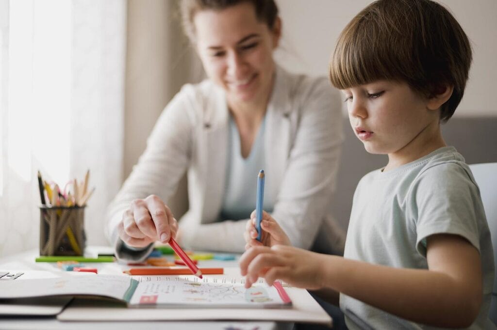 10 dicas de como organizar o cantinho de estudos das crianças; mãe observa filho desenhando em papel sobre mesa