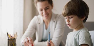 10 dicas de como organizar o cantinho de estudos das crianças; mãe observa filho desenhando em papel sobre mesa