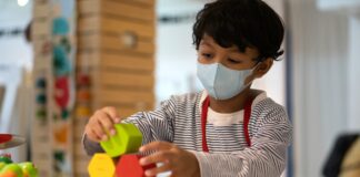 Unicef pede a prefeitos que priorizem a reabertura segura das escolas; criança de máscara brinca com madeiras coloridas em sala de aula