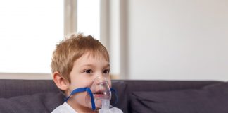 Consumo de ômega-3 pode prevenir asma em crianças, diz estudo; criança está sentada e respira com Máscara de oxigênio