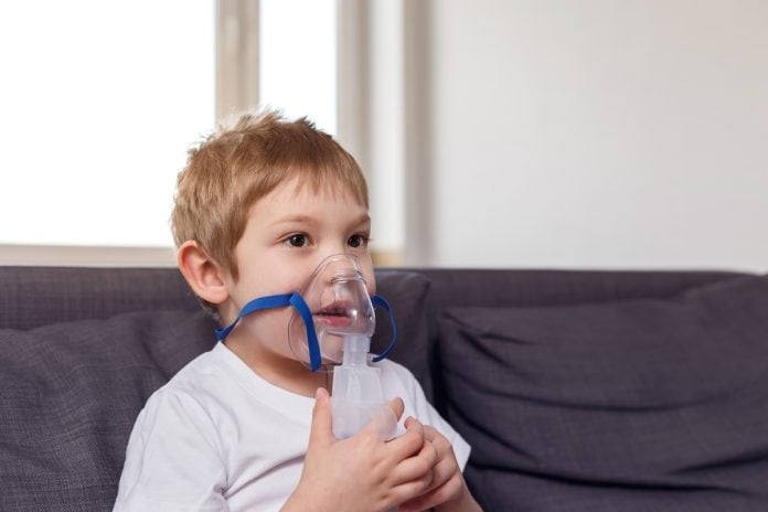 Consumo de ômega-3 pode prevenir asma em crianças, diz estudo; criança está sentada e respira com Máscara de oxigênio