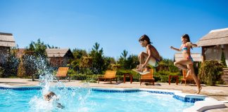 Férias em família: como se divertir sem prejudicar o orçamento; duas crianças pulam na piscina de resort