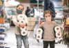 Você costuma levar o seu filho ao supermercado?; duas meninas de máscara e casacos seguram rolos de papel higiênico com os braços
