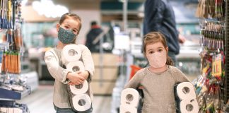 Você costuma levar o seu filho ao supermercado?; duas meninas de máscara e casacos seguram rolos de papel higiênico com os braços