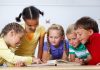 Como lidar com a transição da Educação Infantil para o Fundamental; 5 alunos de etnias diversas olham para livro sobre a mesa