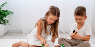 Como saber a hora de deixar a criança sozinha em casa?; menina e menino brincam no chão com peças de encaixe e ferramentas de brinquedo