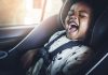 Nova lei de trânsito: o que muda no transporte de crianças e bebês; bebê rindo de boca aberta está sentado em cadeirinha dentro de veículo