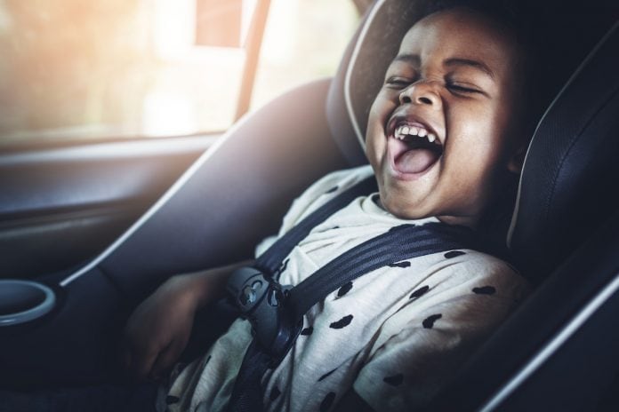 Nova lei de trânsito: o que muda no transporte de crianças e bebês; bebê rindo de boca aberta está sentado em cadeirinha dentro de veículo