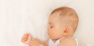 Como fazer o bebê dormir sozinho: conheça as principais técnicas de sono; bebê dorme na cama com o corpo de lado