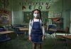 Pandemia pode afetar uma geração inteira de crianças, alerta Unicef; menina em pé dentro de sala de aula com máscara