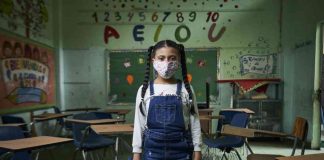 Pandemia pode afetar uma geração inteira de crianças, alerta Unicef; menina em pé dentro de sala de aula com máscara