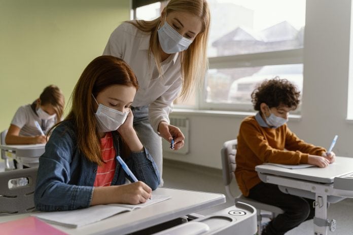 Crianças e professora na escola com máscaras