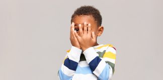 Violência doméstica contra crianças:Menino assustado cobrindo o rosto com as duas mãos