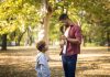 Filhos disciplinados: como chegar ao equilíbrio entre a punição e a permissividade; pai conversa com o filho em meio a parque ao ar livre faz sinal de 'joia' com a mão