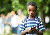 Exclusão escolar na pandemia afeta mais as crianças entre 6 e 10 anos; menino negro de mochila nas costas olha fixamente para a câmera