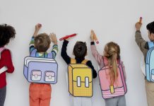 O aprendizado das crianças que acontece nos 'corredores', fora da sala de aula; 5 alunos de mochilas ilustradas na imagem desenham em quadro branco