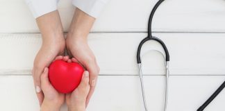 HCor oferece atendimentos gratuitos para crianças com cardiopatia; mãos de um adulto envolvem mãos de uma criança que tem um coração vermelho e do lado há um estetoscópio