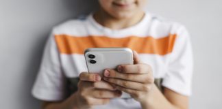 Crianças e celular: o que considerar antes de comprar o aparelho para o filho; criança segundo celular com as duas mãos