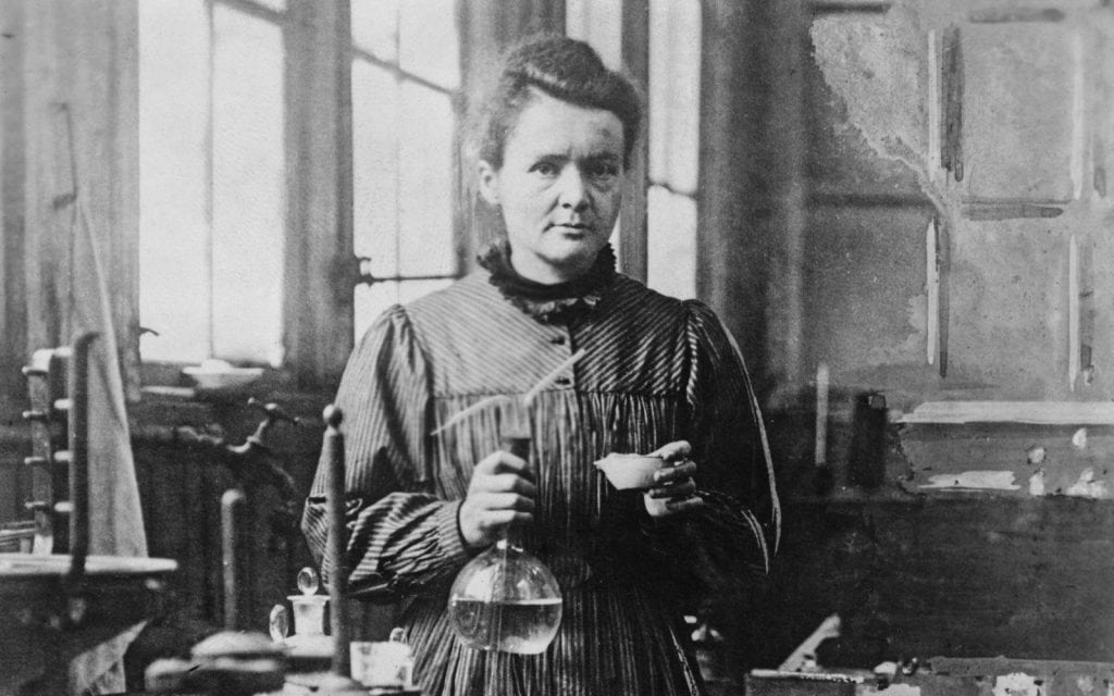 Livro "Marie Curie no país da ciência" narra a vida de uma das maiores cientistas da história; imagem de Marie Curie fazendo experimentos no laboratório