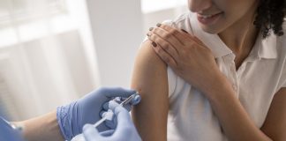 Sem vacinas, imunização de professores não avança no país; mulher recebe vacina no braço