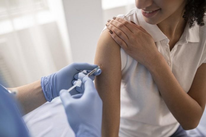 Sem vacinas, imunização de professores não avança no país; mulher recebe vacina no braço
