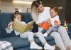 Crianças introvertidas vs extrovertidas: desafios na pandemia; uma criança lendo enquanto outra criança está brincando no colo da mãe
