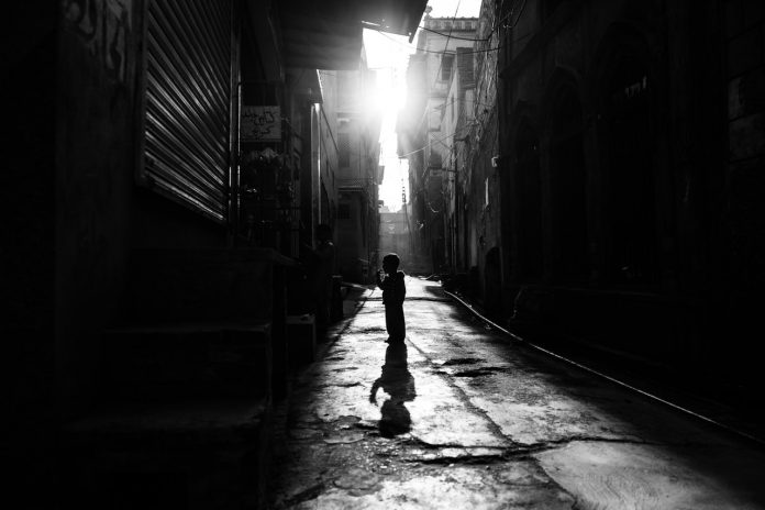 Os jabutis na árvore e os órfãos da Covid; criança anda em rua deserta e escura, foto em preto e branco