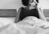 Depressão pós-parto - agora chamado perinatal, visto que se inicia durante a concepção do bebê - traz medos, dificuldades e incertezas; mulher grávida deitada na cama segura lencinho com a mão perto do nariz