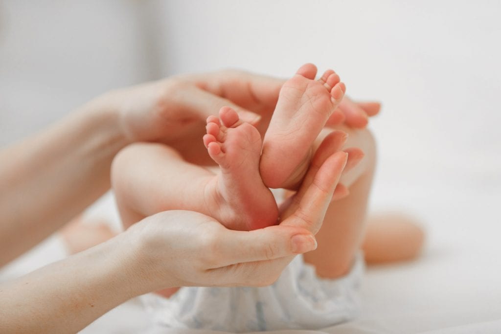 Dia Nacional do Teste do Pezinho: conquistas e desafios a enfrentar; mãos de adulto seguram pés de recém-nascido