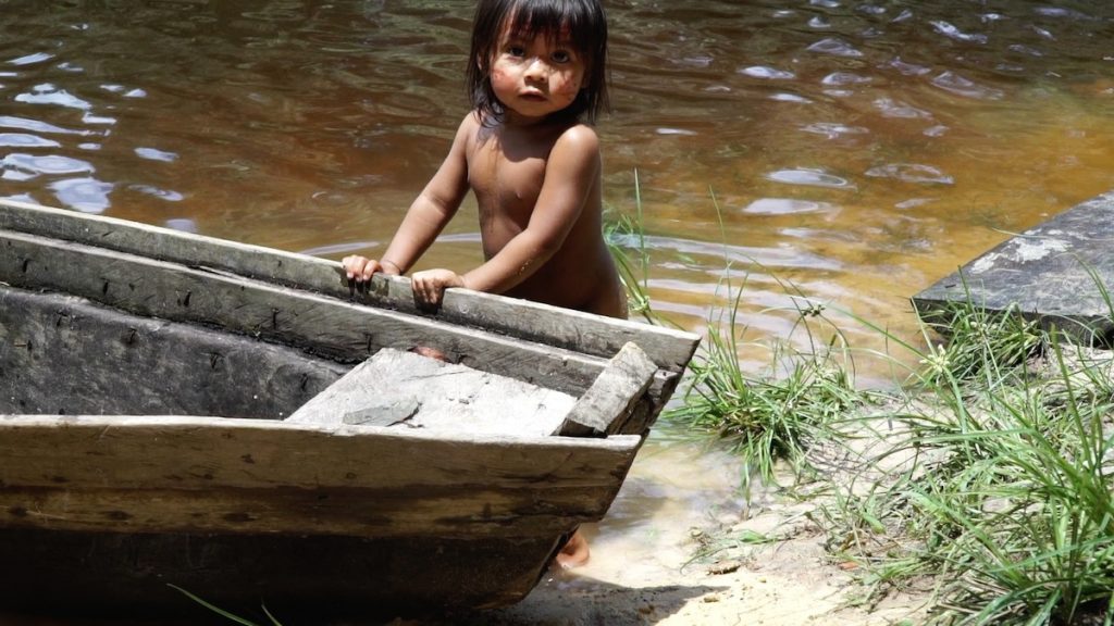Para assistir online: a infância de povos indígenas em 6 curtas-metragens; menina índia apoia mãos sobre barco na beira de um rio, cena do curta "Dairé Késia"