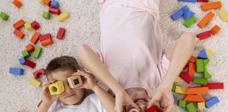 Férias casa: dicas de brincadeiras para mais interação e menos tecnologias; duas crianças deitadas no chao brincam com peças de encaixe