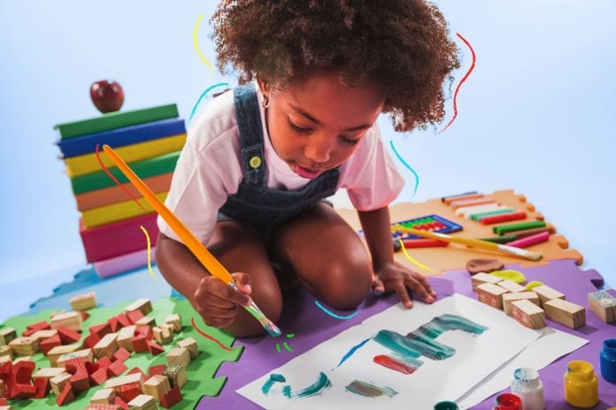 Pintura e aquarela: benefícios para o desenvolvimento infantil; criança com pincel na mão pintando no papel