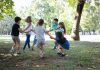 Contato com a natureza beneficia a saúde física e mental das crianças; crianças brincam de mãos dadas em roda em área verde ao ar livre